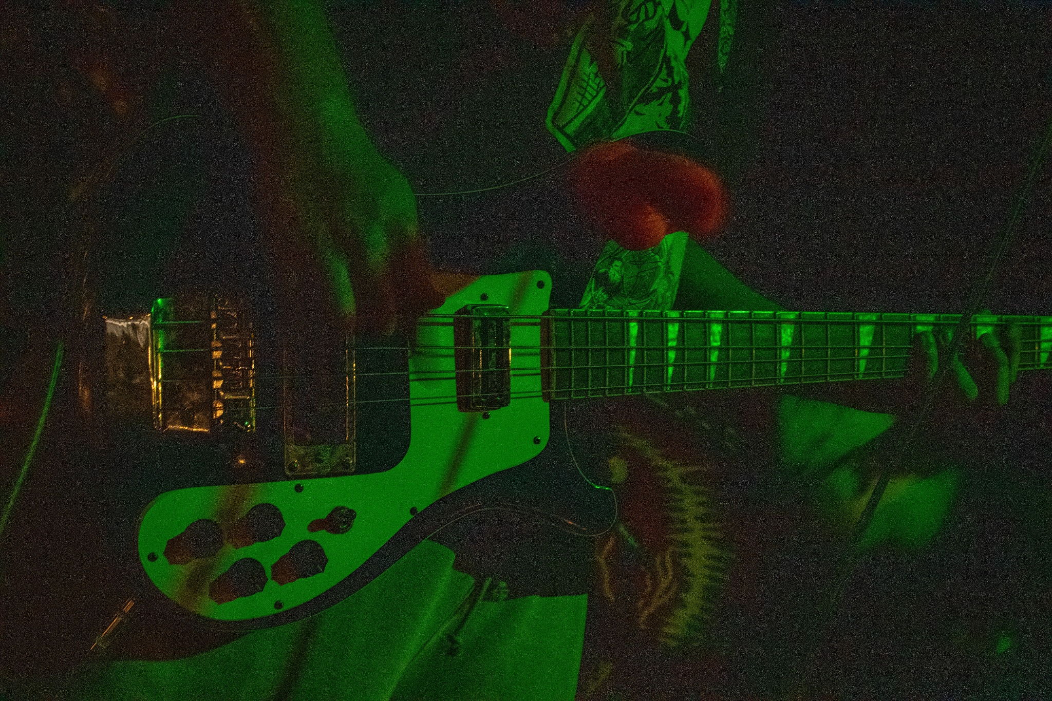 Close-up of Guttercunt bass performance under green light